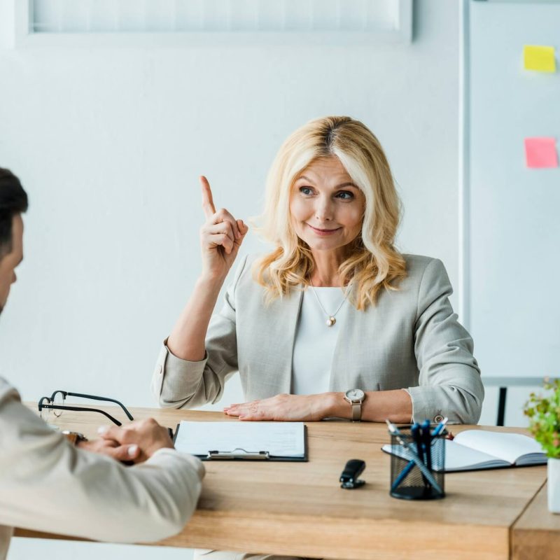 selective-focus-of-happy-recruiter-gesturing-near-employee-in-office.jpg